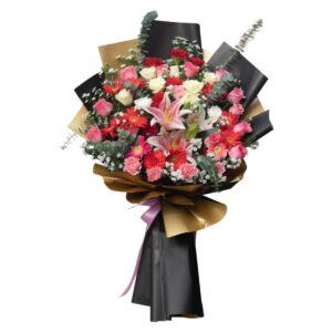 A luxurious bouquet featuring a vibrant mix of pink lilies, red and white roses, carnations, gerberas, baby's breath, and eucalyptus, wrapped in elegant black and gold paper with a pink ribbon