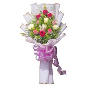 Bouquet of red, pink, and white roses with pink lily and greenery, wrapped in white and gold-trimmed paper with a pink ribbon
