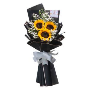 Bouquet of three bright sunflowers with white aster fillers, wrapped in black paper and tied with a light gray ribbon