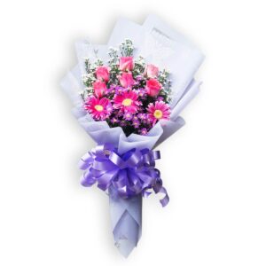 A beautiful bouquet featuring pink roses, pink gerbera daisies, and purple filler flowers, wrapped in white and purple paper and tied with a large lavender ribbon